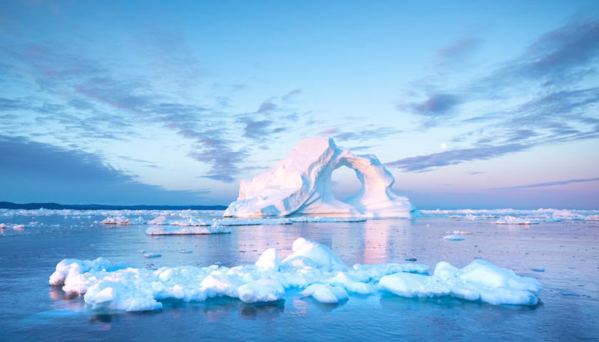 iceberg en forme de bloc troué sur fond de ciel bleu et rose